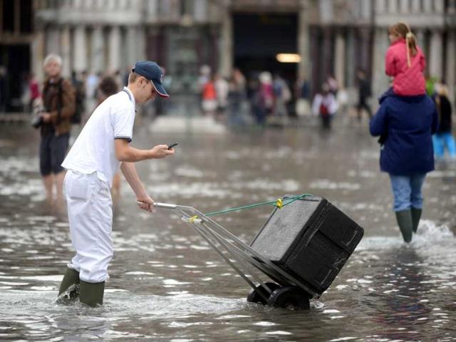 An employee walks on the flooded St Mark's square as he delivers goods during the first "acqua alta" of the season in Venice. The "acqua alta", a convergence of high tides and a strong sirocco, reached 105 centimeters. AFP photo