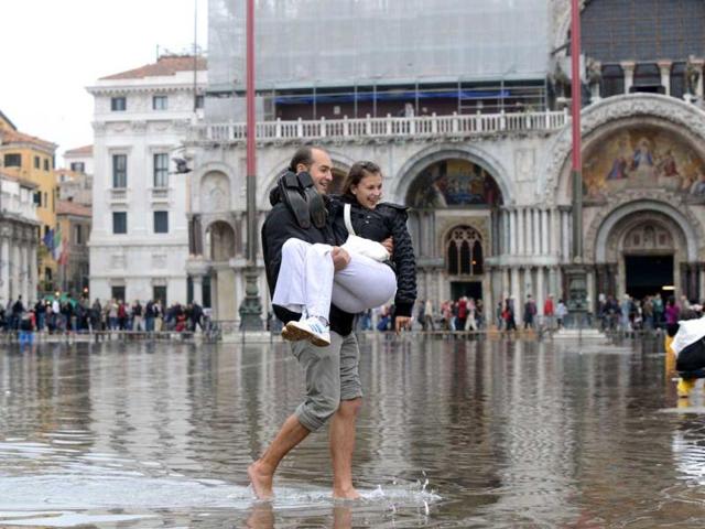 A tourist holds his partner in his arms on a flooded St Mark's square during the first "acqua alta" of the season in Venice. The "acqua alta", a convergence of high tides and a strong sirocco, reached 105 centimeters. AFP photo