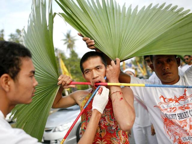 A devotee of Ban Tha Rua Chinese shrine is helped with piercing palm branches through his cheeks during a procession celebrating the annual vegetarian festival in Phuket. (Reuters/Damir Sagolj)