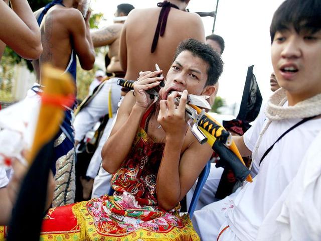 A devotee of Ban Tha Rua Chinese shrine with knives pierced through his cheeks takes part in a procession celebrating the annual vegetarian festival in Phuket. (Reuters/Damir Sagolj)