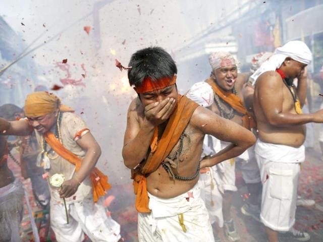 Devotees of Ban Tha Rua Chinese shrine turn away from exploding firecrackers during a procession celebrating the annual vegetarian festival in Phuket. (Reuters/Damir Sagolj)