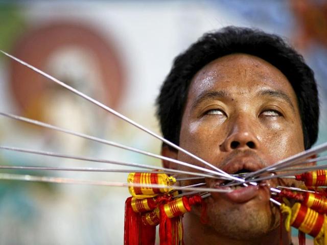 A devotee of Ban Tha Rua Chinese shrine with his cheeks pierced sits in trance before a procession celebrating the annual vegetarian festival in Phuket. (Reuters/Damir Sagolj)
