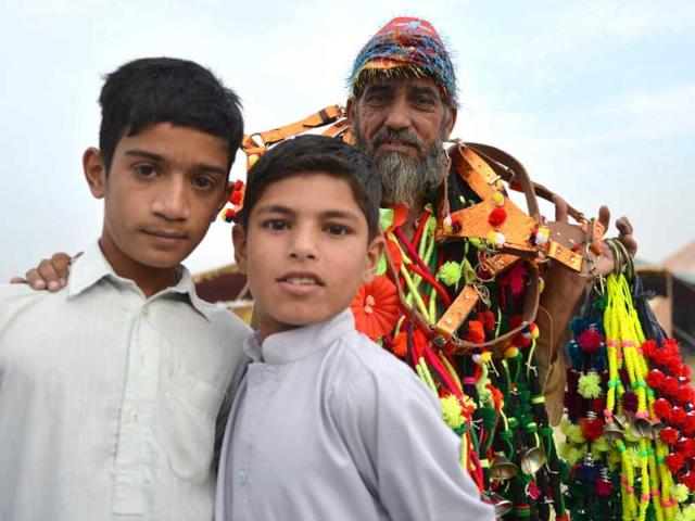 Youngsters pose a photograph with a vendor carrying animal decorations at the one of the main animal markets setup for the forthcoming Eid Al-Adha festival or the Feast of Sacrifice in Islamabad. AFP Photo