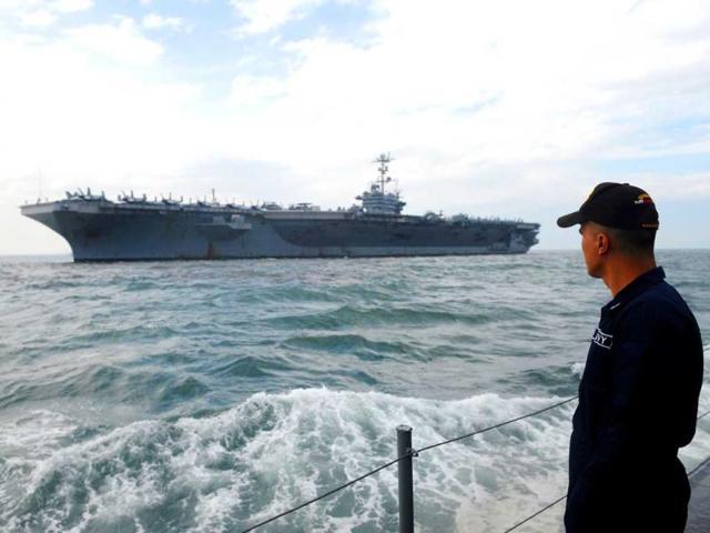 A Philippine Navy personnel looks at the nuclear-powered USS George Washington Nimitz-class aircraft carrier as it arrives in Manila. USS George Washington is in Manila for a short goodwill visit that aims to further enhance ties between the US and the Philippines through community relations projects and professional exchanges between the two countries. AFP PHOTO