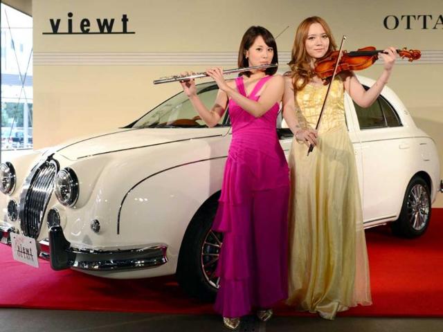 Japanese flutist Akiyo Ueta (L) and violinist Asuka Ochi (R) pose in front of Mitsuoka Motors' special edition 1200-cc classic sedan car, 'Viewt OTTAVA' during its press preview in Tokyo. AFP PHOTO
