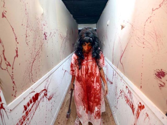 An actor plays the role of Lizzie Borden at Killers: A Nightmare Haunted House, at Clemente Soto Vélez Cultural Center. Visitors can see a exhibit of drawings and other artifacts once belonging to real-life monsters such as John Wayne Gacy and Charles Manson, donated by an anonymous collector. AFP PHOTO