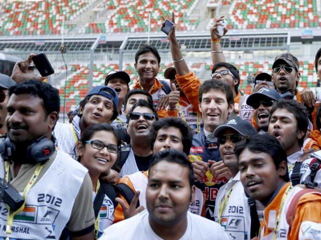 Red Bull driver Mark Webber, centre, of Australia poses for a photo with track marshals ahead of the Indian Formula One Grand Prix at the Buddh International Circuit in Greater Noida. AP Photo