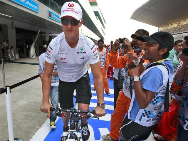 Mercedes driver Michael Schumacher of Germany rides his bike down pit lane ahead of the Indian Formula One Grand Prix at the Buddh International Circuit in Greater Noida. AP Photo