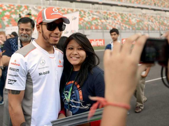 McLaren Mercedes driver Lewis Hamilton (2L) of Britain poses with a fan at The Buddh International circuit in Greater Noida. AFP Photo