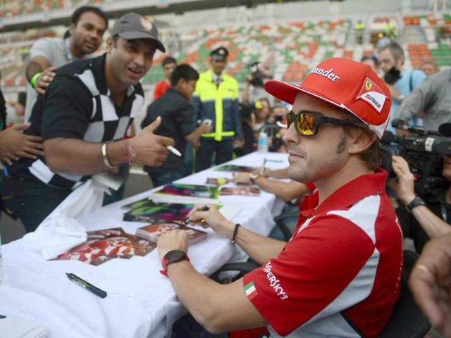 Ferrari driver Fernando Alonso (R) of Spain poses for a fans during an autograph session at The Buddh International circuit in Greater Noida. AFP Photo