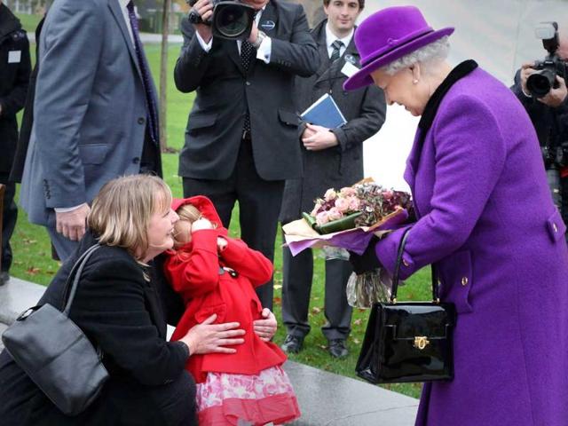 Bethany Wiles, aged three, covers her face and is held by her mother Rae Wiles after giving flowers to Britain's Queen Elizabeth at a ceremony at Jubilee Gardens in London. Reuters/Peter Macdiarmid