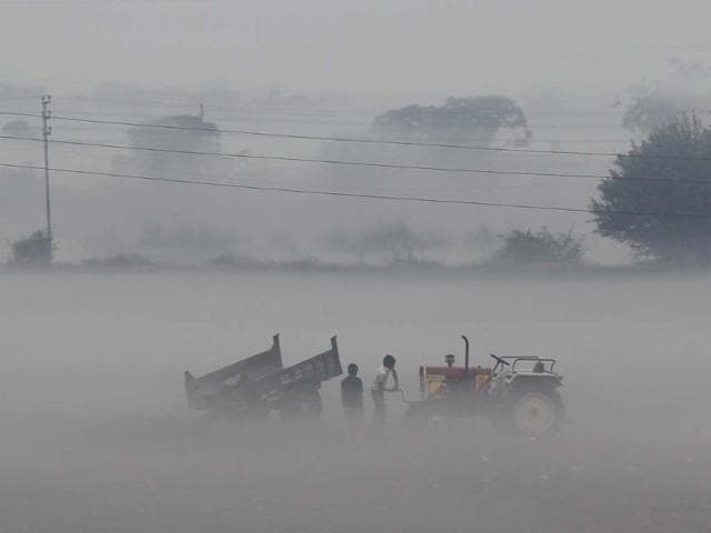 A man starts the engine of a tractor during a foggy morning in a field along the Delhi-Noida highway. REUTERS