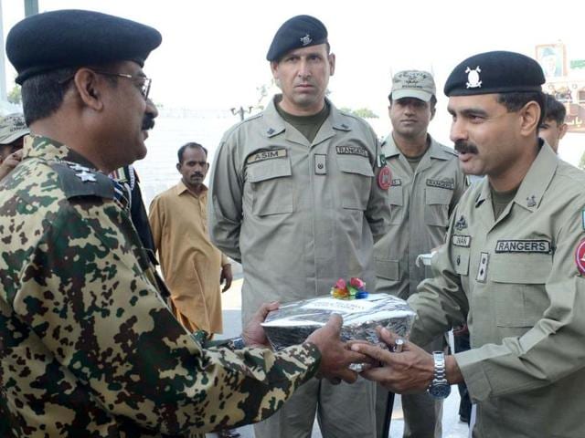 Pakistani Rangers wing commander Adnan (R) presents a box of sweets to Indian Border Security Force (BSF) Deputy Inspector General (DIG), Baby Joseph (L), during Eid al-Adha at the India-Pakistan Wagah Border. AFP Photo