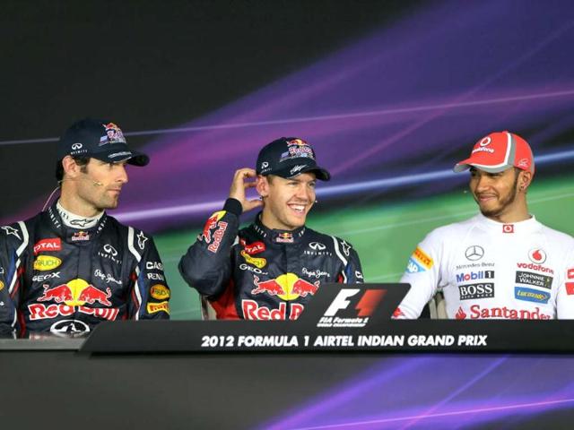 Red Bull driver Sebastian Vettel, centre, of Germany smiles as he sits with teammate Mark Webber of Australia at a press conference following his win in the qualifying session for the Indian Formula One Grand Prix at the Buddh International Circuit in Noida, on the outskirts of New Delhi. AP Photo