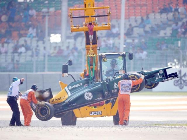 Track marshals hoist the car of Caterham-Renault driver Heikki Kovalainen of Finland after he skid off the track during the qualifying session at The Buddh International circuit in Greater Noida, on the outskirts of New Delhi . AFP Photo
