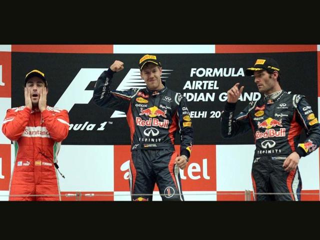 Winner Red Bull-Renault driver Sebastian Vettel of Germany (C) celebrates at the podium as second-placed Ferrari driver Fernando Alonso of Spain (L) and third-placed Red Bull-Renault driver Mark Webber of Australia watch after victory at the Formula One Indian Grand Prix at The Buddh International circuit in Greater Noida . AFP Photo