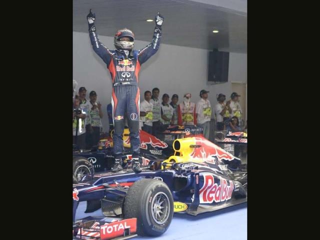 Red Bull driver Sebastian Vettel of Germany stands on his car as he celebrates his win at the Indian Formula One Grand Prix at the Buddh International Circuit in Noida. (AP Photo/Mark Baker)