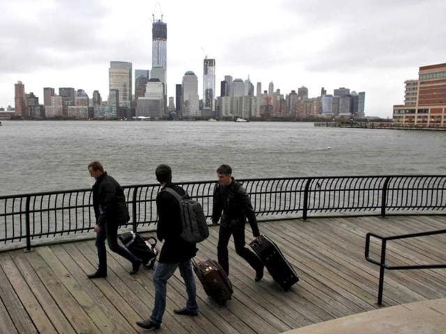 The skyline of New York's Lower Manhattan and One World Trade Center are seen while people pull their luggage at Waterfront in New Jersey. Tens of millions of East Coast residents scrambled on Sunday to prepare for Hurricane Sandy. Reuters/Eduardo Munoz