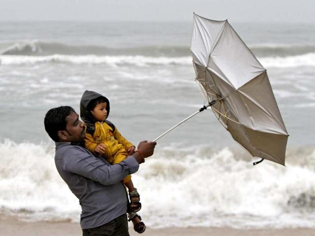 A man carrying his child tries to hold an umbrella at Marina beach in Chennai. Reuters Photo