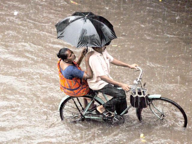 A man on a cycle rides through a water-logged road in Chennai. Agency Photo