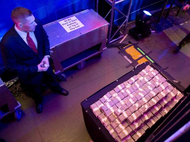A security guard keeps watch over a stack of money backstage during the World Series of Poker Final Table event in Las Vegas. AP Photo/Julie Jacobson
