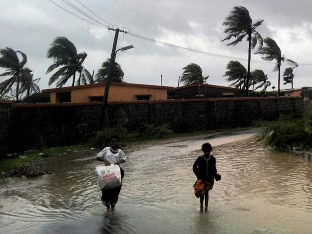 People run for a safer place during rains and strong winds in Puducherry. PTI Photo