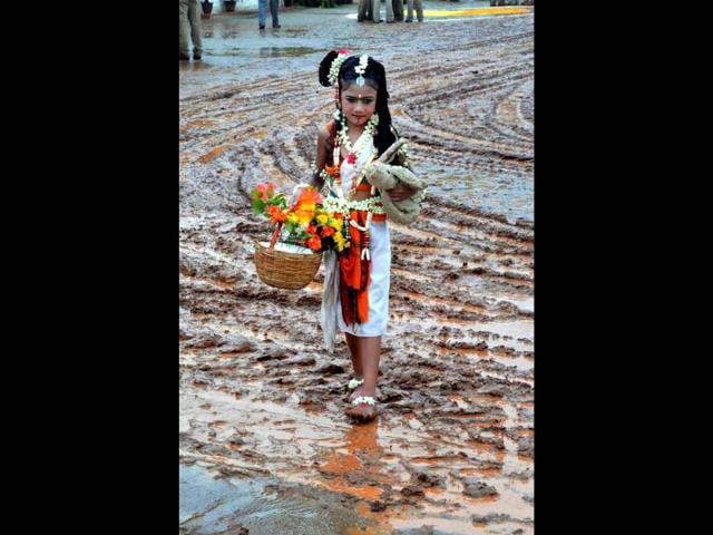 A child, dressed for Kannada Rajyothsava cultural programmes, walking in a mudddy field as the function was cancelled after rains due to Nilam cyclone in Chikmagalur in Karnataka . PTI Photo