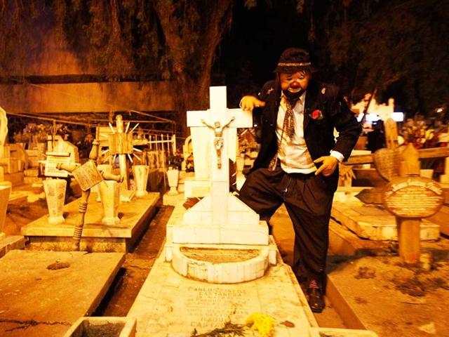 A man dressed as a clown stands between graves during the Day of the Dead celebrations at a cemetery in Mixquic. On the Day of the Dead, Mexicans pay homage to their dead relatives by preparing meals and decorating their graves. Reuters photo