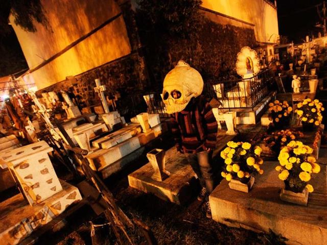 A masked man walks between graves during the Day of the Dead celebrations at a cemetery in Mixquic. On the Day of the Dead, Mexicans pay homage to their dead relatives by preparing meals and decorating their graves. Reuters photo