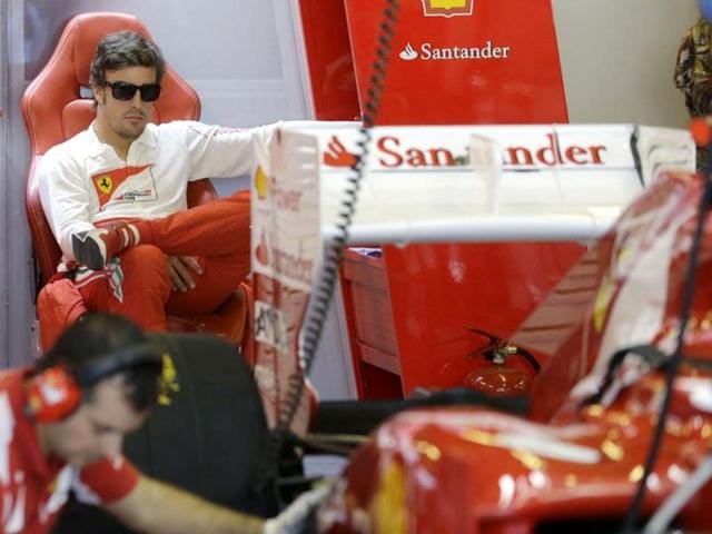 Ferrari driver Fernando Alonso of Spain watches as his car is serviced in the pits during the third free practice at the Yas Marina racetrack, in Abu Dhabi, United Arab Emirates. AP Photo