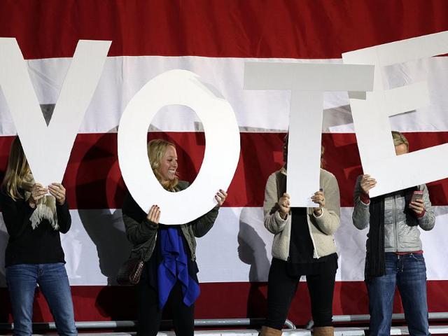 Women-hold-up-signs-spelling-vote-on-a-stage-being-prepared-for-a-speech-by-President-Barack-Obama-at-a-campaign-rally-at-the-Community-College-of-Aurora-in-Denver-AP-Brennan-Linsley