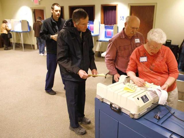 Poll workers Don Allison (2nd-R) and Bertha Janis Â¨ chief Inspector of the polling stations go over a ballot that was rejected by the machine while voters wait in line to cast their vote in the Presidential elections in Janesville Wisconsin. AFP photo