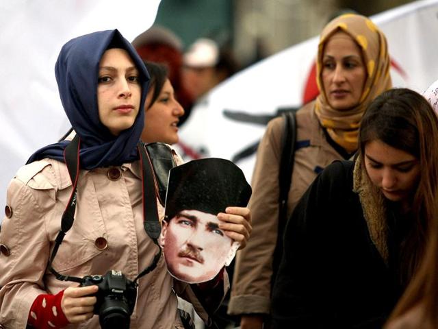 A Turkish woman holds a Mustafa Kemal Ataturk's mask during the 74th anniversary of his death, at the courtyard of the Ottoman-era Dolmabahce Palace in Istanbul. AFP/Str