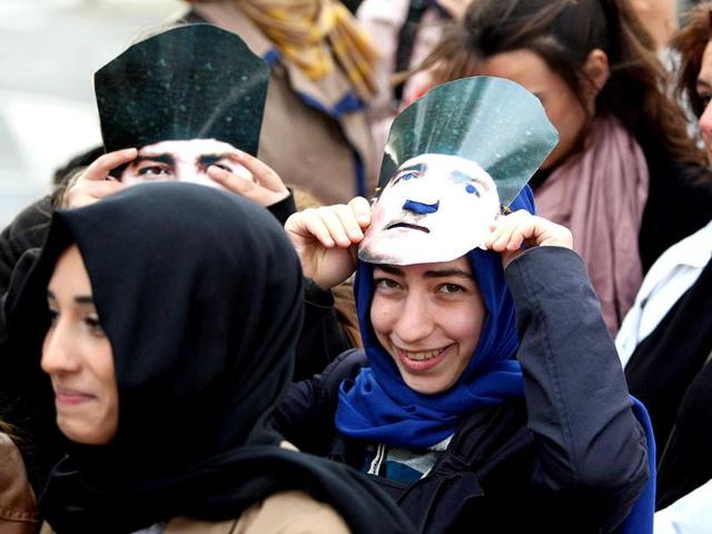 Turkish muslim women wear a Mustafa Kemal Ataturk's mask during the 74th anniversary of his death, at the courtyard of the Ottoman-era Dolmabahce Palace in Istanbul. AFP/Str