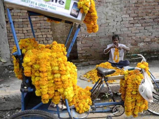Rickshaw puller Naresh prepares a marigold flower garland for customers for Diwali in New Delhi. AFP PHOTO Rickshaw puller Naresh prepares a marigold flower garland for customers for Diwali in New Delhi. AFP PHOTO