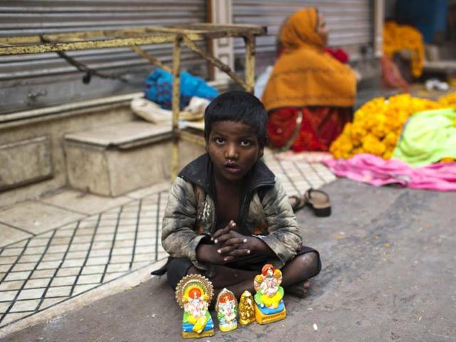 A young street child looks up as he sells small Hindu effigies for the Diwali festival in the Old Quarters of New Delhi. AFP PHOTO A young street child looks up as he sells small Hindu effigies for the Diwali festival in the Old Quarters of New Delhi. AFP PHOTO