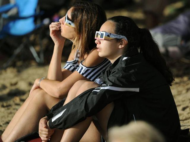 Two women wear special glasses to view the solar eclipse from the beach at Palm Cove in Australia's Tropical North Queensland. (AFP Photo)