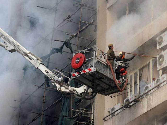 A firefighter douses a fire that broke out in a fifteen story building, Himlaya House, in New Delhi. AFP