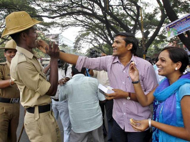 Activists of Akhil Bharatiya Vidyarthi Parishad, or All Indian Student Council, offer sweets to a policeman to celebrate on hearing the news that Mohammed Ajmal Kasab, the lone surviving gunman from the 2008 terror attacks on Mumbai, was executed, in Bangalore. (AP Photo/ Aijaz Rahi)