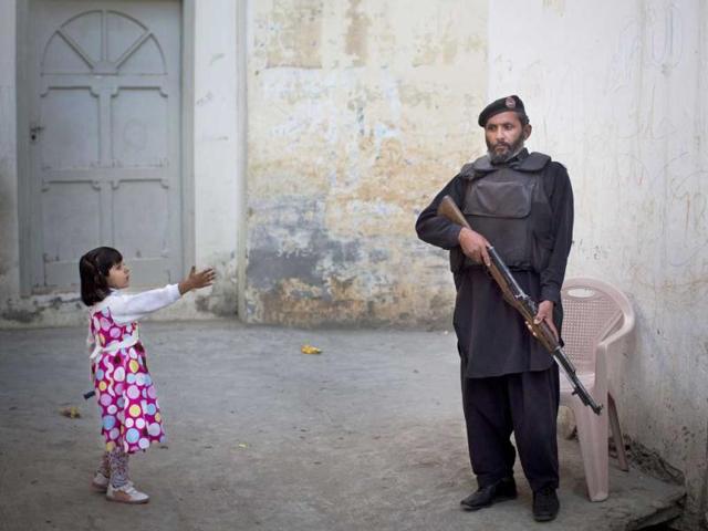 A young girl reaches out to greet a Pakistani policeman securing the road outside Kainat Riaz's home in Mingora, Swat Valley, Pakistan. AP/Anja Niedringhaus