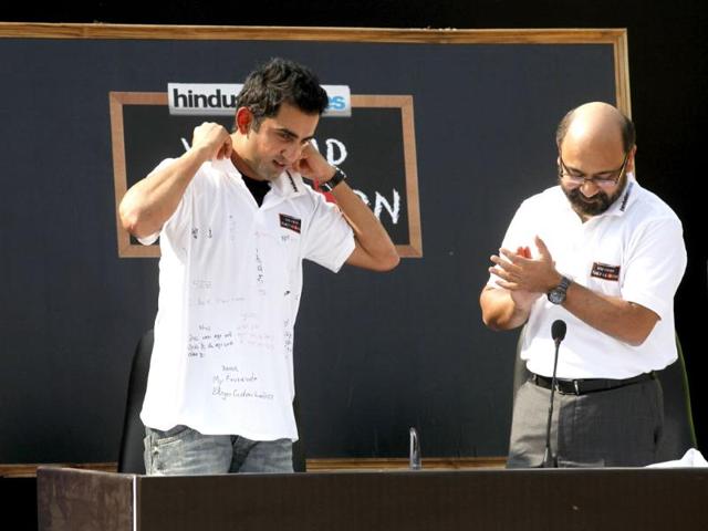Cricketer Gautam Gambhir wearing the T-shirt with messages written by children as Shantanu Bhanja looks on during a Hindustan Times initiative 'You Read They Learn' programe at Pratham centre at Trilokpuri in New Delhi. HT/Virendra Singh Gosain
