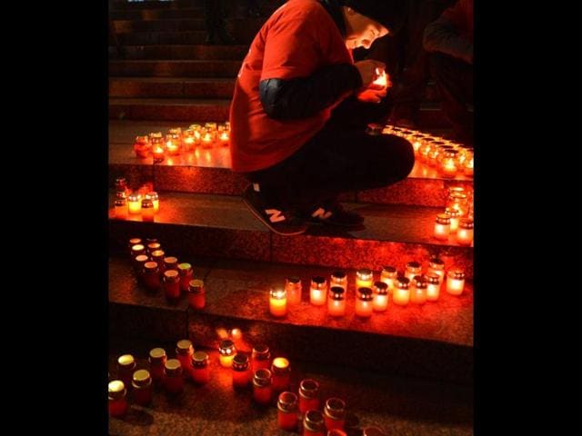 A boy lights a candle to set a symbolic red ribbon during an HIV/AIDs rally in the center of the Ukrainian capital of Kiev. AFP/Sergei Supinsky