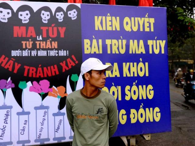 A man stands next to a poster warning that drug using is leading to HIV affection at the venue of a meeting on World's AIDS Day in Hanoi. AFP