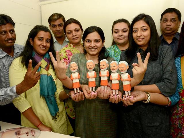 Supporters of the Gujarat chief minister Narendra Modi pose with clay figurines of the politician called 'Icon Tops' in Ahmedabad. (AFP Photo)