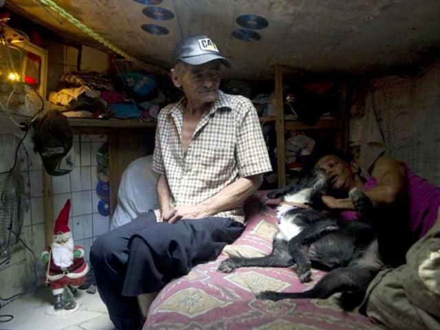 Colombian Miguel Restrepo, rests with his wife Maria Garcia and their dog on a bed inside a sewer in Medellin, Antioquia department, Colombia. AFP Photo
