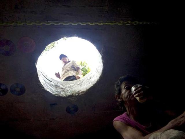 Colombian Miguel Restrepo stands outside the sewer where he lives while his wife drinks coffee inside in Medellin, Antioquia department, Colombia. Restrepo, 62, is a homeless man who has lived with his wife for more than twenty years in a sewer, near Medellin's downtown. AFP Photo