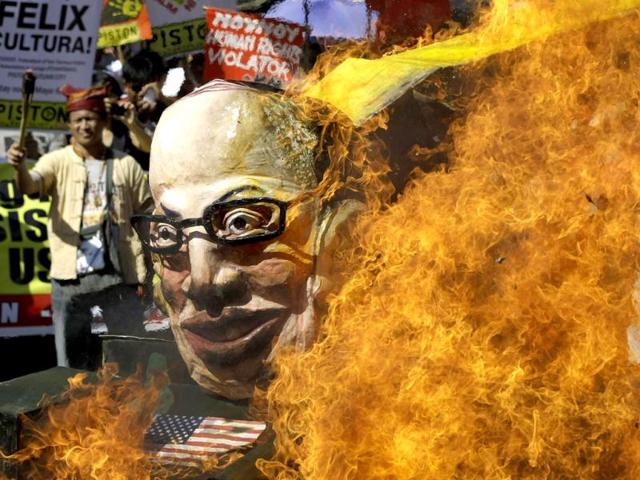 Protesters burn an effigy of Philippine President Benigno Aquino III on board a mock tank as they commemorate International Human Rights Day near the Presidential Palace in Manila, Philippines. The group called the Aquino administration as alleged human rights violators. (AP Photo/Aaron Favila)