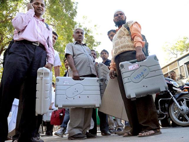 Election officials wait with Electronic Voting Machines to leave for polling stations from a distribution centre at Dholka near Ahmedabad, ahead of Gujarat Assembly polls. PTI Photo