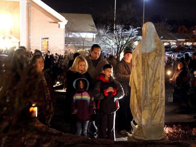A family prays at a statue of the Virgin Mary outside Saint Rose of Lima church in Newtown, Connecticut. AP photo