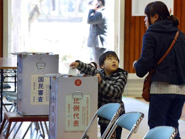 A boy helps his mother (R) to cast a vote in the general election at a polling station in Funabashi, suburban Tokyo. Voters began casting ballots in Japan for a general election likely to return long-ruling conservatives to power after three years in the wilderness. AFP photo